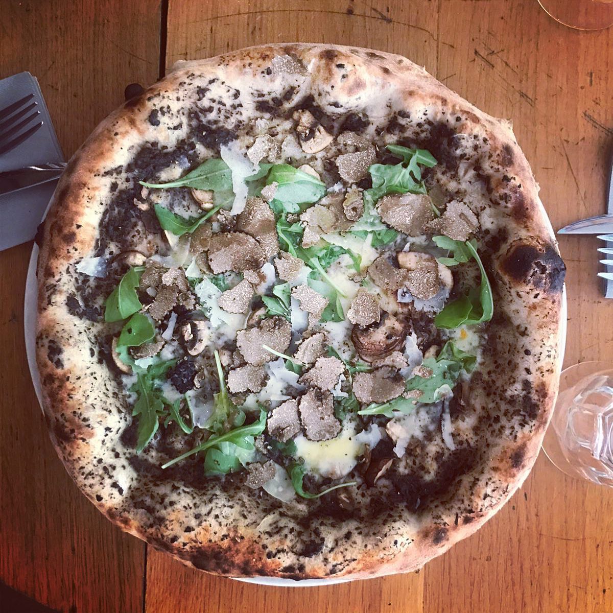 Pizza Truffe : crème de truffe, roquette, grana et champignons, croûte léopard napolitaine
